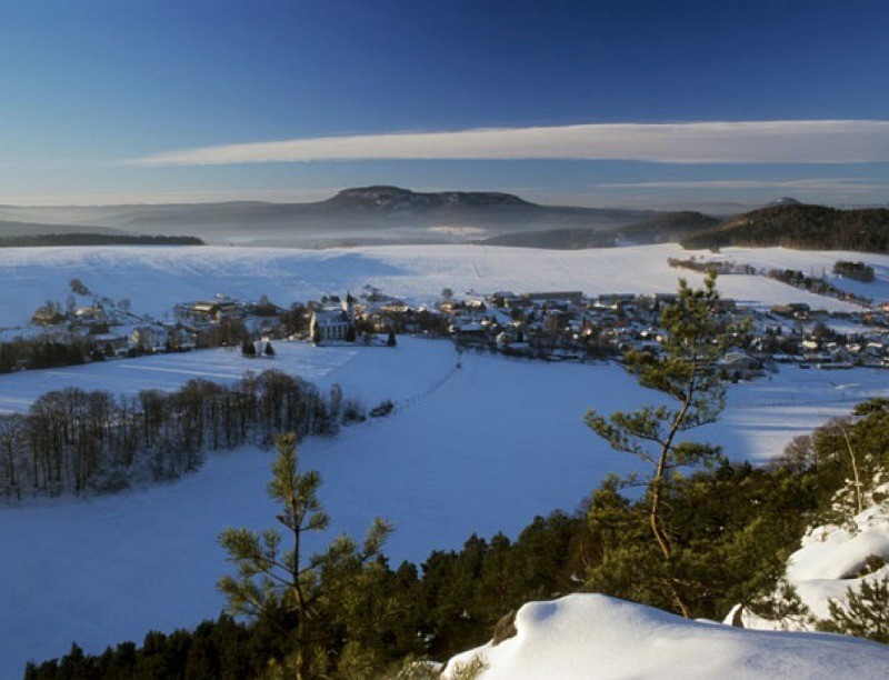 Blick von oben auf ein verschneites Dorf im Tal