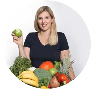 Porträt von Julia Bierenfeld mit viel frischem Obst und Gemüse