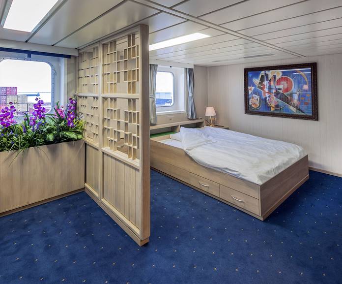 Passagierkabine eines Frachtschiffes mit großem Bett und Blick nach draußen. 