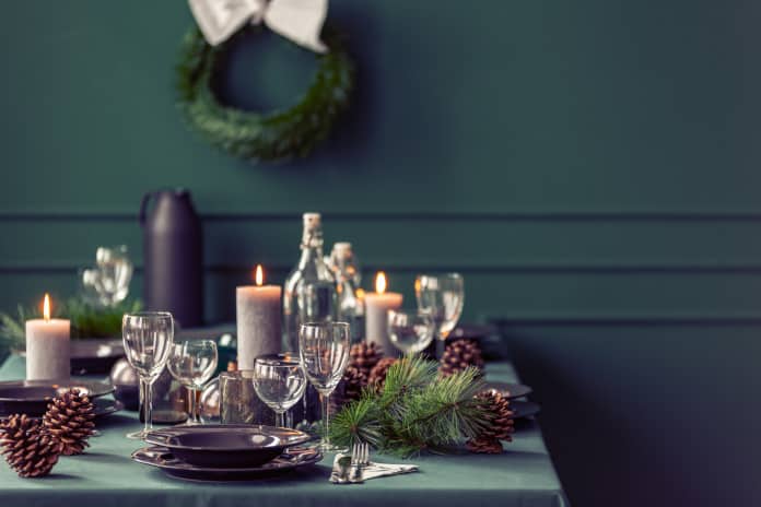 Ein weihnachtlich gedeckter Tisch, im Hintergrund hängt ein Kranz an der Wand