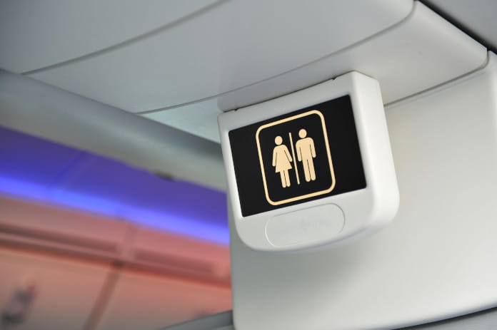 Eine Anzeige-Tafel im Flugzeug mit den Symbolen für Frau und Mann, als Hinweis auf das WC.