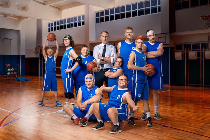 Eine Basketballmannschaft mit Behinderung, in der Mitte der Trainer.