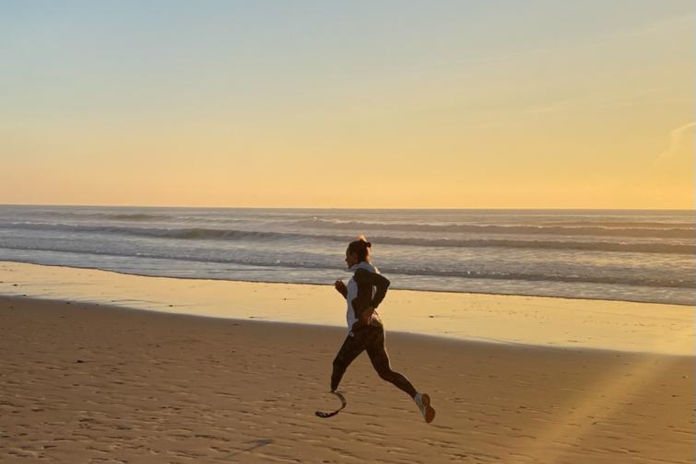 Eine Frau joggt am Strand, sie trägt ein Beinprothese