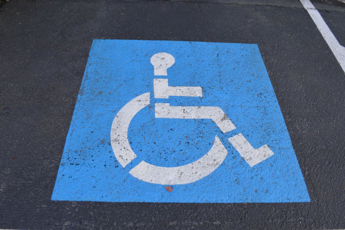 Asphalt mit einem weißen (gemalten) Rollstuhlfaher auf blauen Hintergrund