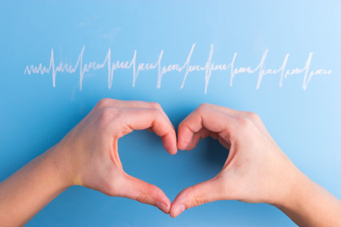 Zwei Hände formen ein Herz vor einen blauen Hintergrund. Darüber ist eine Herz-Rhythmus-Linie gezeichnet.