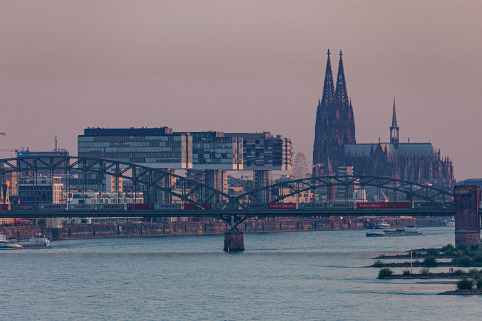 Köln in der Abenddämmerung, Blick auf die Rheinbrücke und den Dom dahinter.