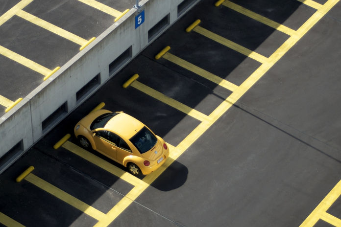 Ein gelbes Auto steht auf einem Parkplatz mit gelben Abtrennstreifen.