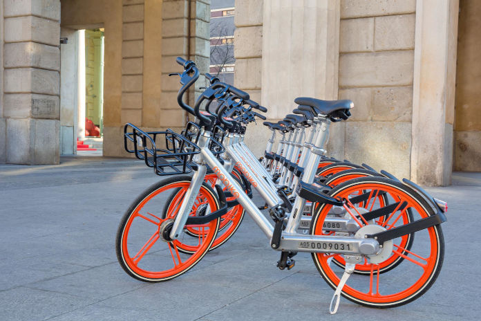 Fahrräder mit oranger Felge stehen aufgereiht. Sie sind von einem Bikesharing-Anbieter.