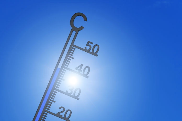 Ein Thermometer vor blauem Himmel mit Sonne.