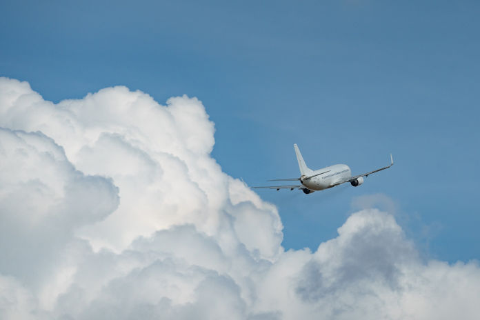 Ein Flugzeug kurz nach dem Start zwischen einer Wolkendecke. Im Hintergrund blauer Himmel.