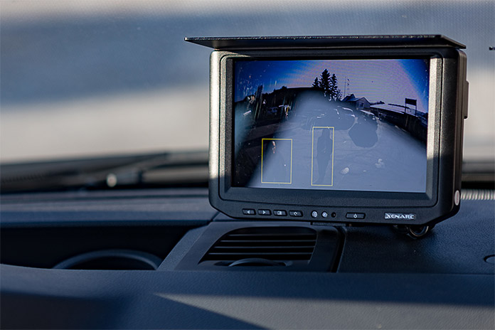 Ein Kamerasystem mit einem Monitor auf der Mittelkonsole im Auto angebracht. Auf dem Bildschirm ist eine markierte Umrandung eine sogenannte Umfelderkennung.