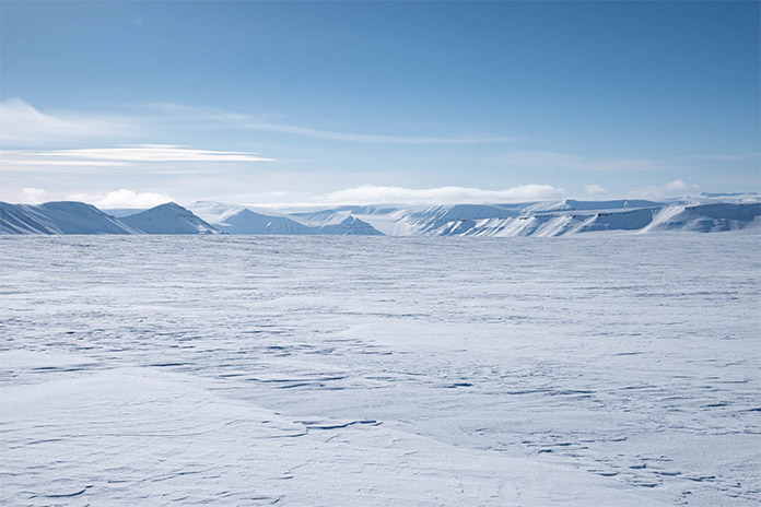 Eine weiße Schneelandschaft mit weißen Schneebergen im Hintergrund.