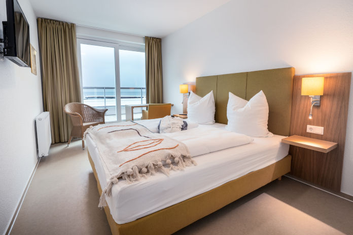 Ein Schlafzimmer eines Penthouses mit Doppelbett und Ausblick auf das Meer.