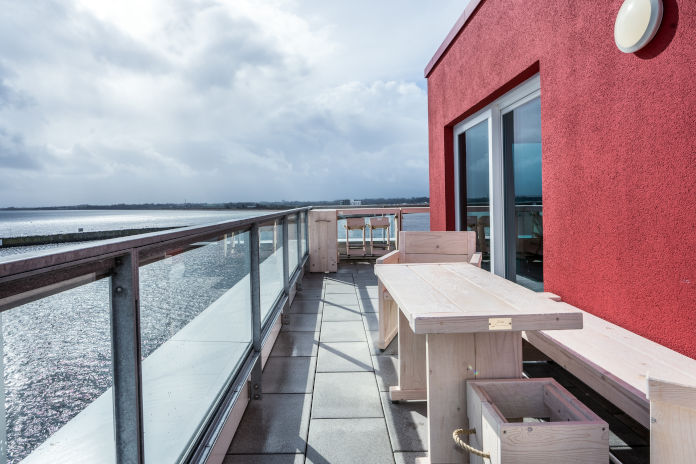 Eine Dachterrasse mit Sitzmöglichkeiten und Ausblick aufs Meer eines Penthouses.