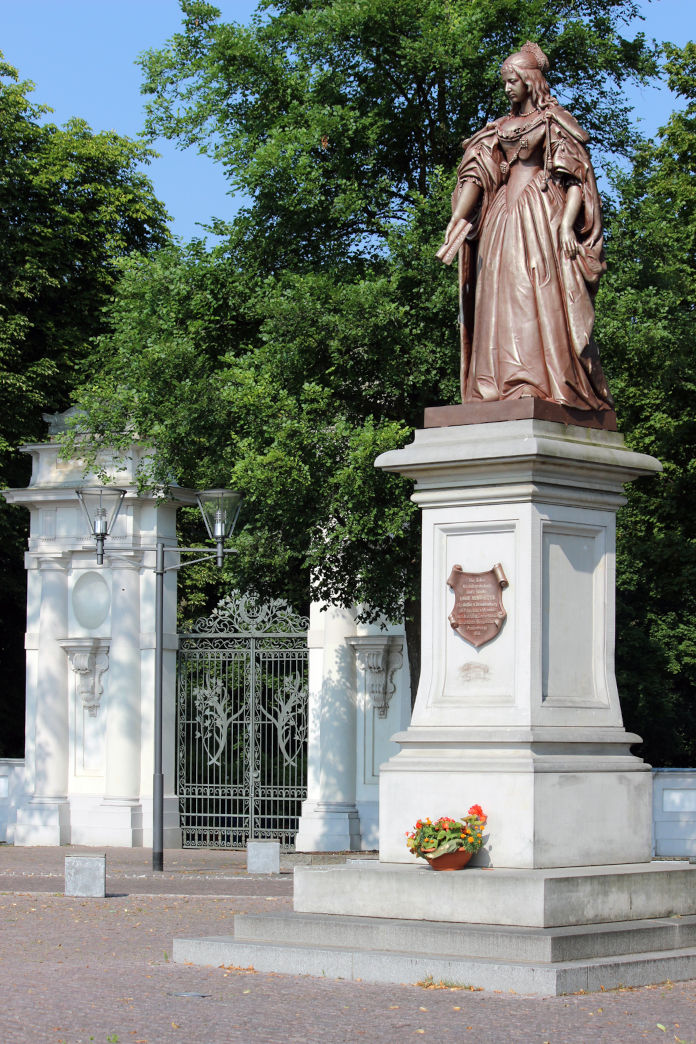 Ein Denkmal für die Kurfürstin Luise Henriette. Die Statue ist in einem braunen Ton gehalten, die Säule aus weißen Stein. Darauf wurde ein Wappen angebracht.