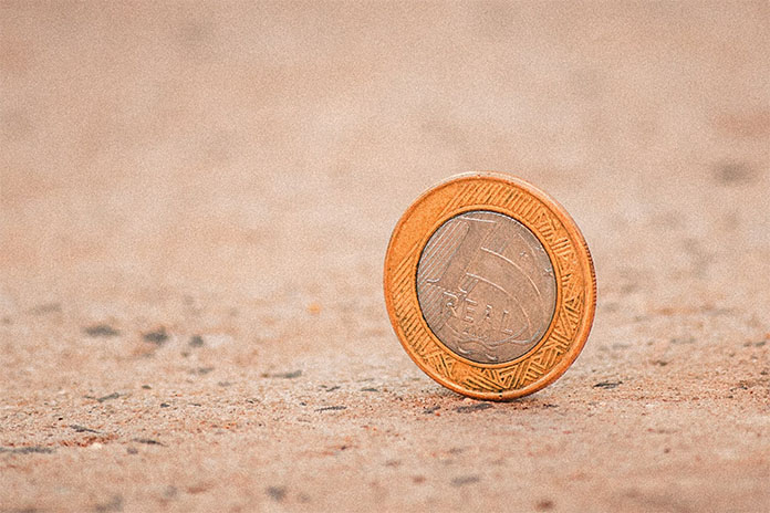 Eine Münze stehend auf einem sandigen Untergrund.