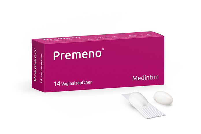 Eine Packung des Produkts "Premeno" von Medintim. Die Packung ist pink und enthält 14 Vaginalzäpfchen. Vor der Packung liegen zwei weiße Zäpfchen, eines davon ist aus der Verpackung herausgenommen.